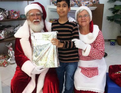 Criança ao centro e ao lado papai Noel e Mamãe Noel