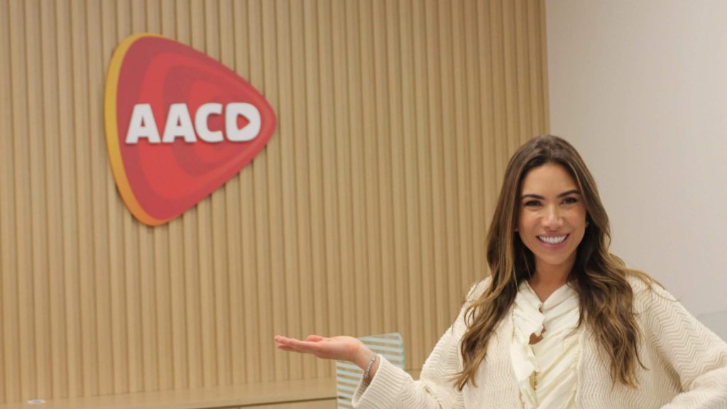 Patrícia Abravanel posa ao lado de logo da AACD