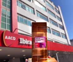 A AACD foi reconhecida como a quarta melhor empresa para atuar no segmento hospitalar segundo a GPTW. Na foto, o troféu da premiação GPTW em frente a fachada da AACD Ibirapuera.