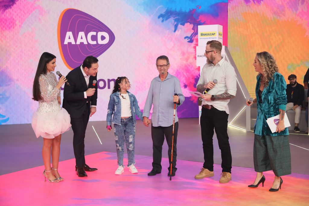 Allice Manuelly e Lécio Siqueira, paciente-símbolo, interagem com artistas no palco do Teleton 2024