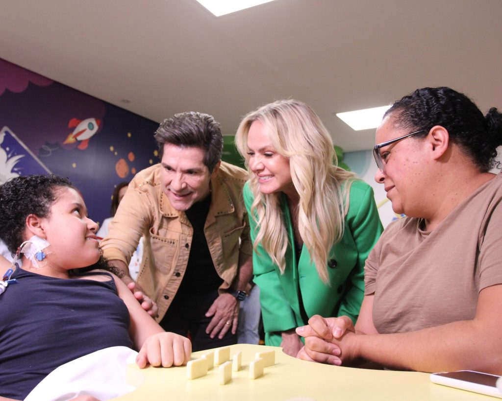 Eliana e Daniel interagem com paciente e sua mãe na brinquedoteca do Hospital Ortopédico AACD