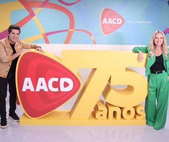 Eliana e Daniel, padrinhos do Teleton, posam no totem de 75 anos da AACD
