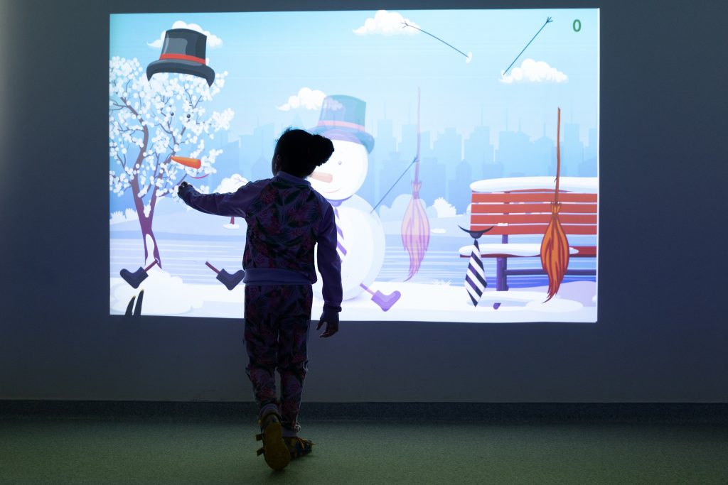 Menina toca em painel de realidade virtual com desenhos de boneco da neve.