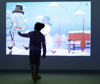 Menina toca em painel de realidade virtual com desenhos de boneco da neve.