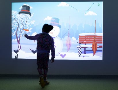 Menina toca em painel de realidade virtual com desenhos de boneco da neve.