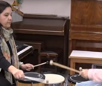 Terapeuta e menina em cadeira de rodas mexem em instrumentos musicais