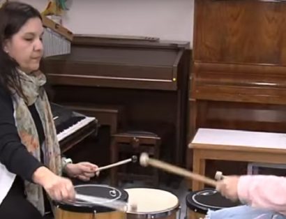 Terapeuta e menina em cadeira de rodas mexem em instrumentos musicais