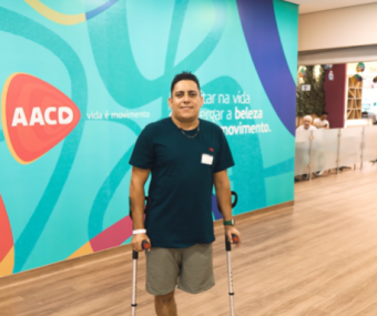 Paciente amputado atrás de fundo institucional da AACD como parte de campanha de conscientização de campanha sobre segurança no trânsito