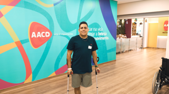 Paciente amputado atrás de fundo institucional da AACD como parte de campanha de conscientização de campanha sobre segurança no trânsito