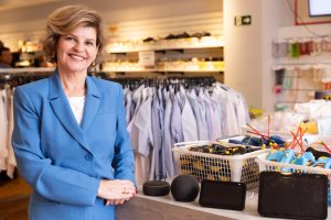 Silvia Paz, superintendente da AACD, no bazar da Instituição ao lado roupas e produtos eletrônicos