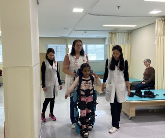 Paciente utiliza o exoesqueleto infantl com auxilio de fisioterapeutas da AACD.