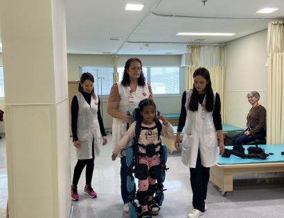 Paciente utiliza o exoesqueleto infantl com auxilio de fisioterapeutas da AACD.