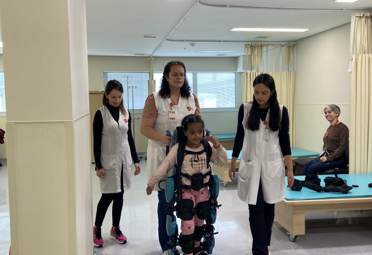 Paciente utiliza o exoesqueleto infantl com auxilio de fisioterapeutas da AACD.