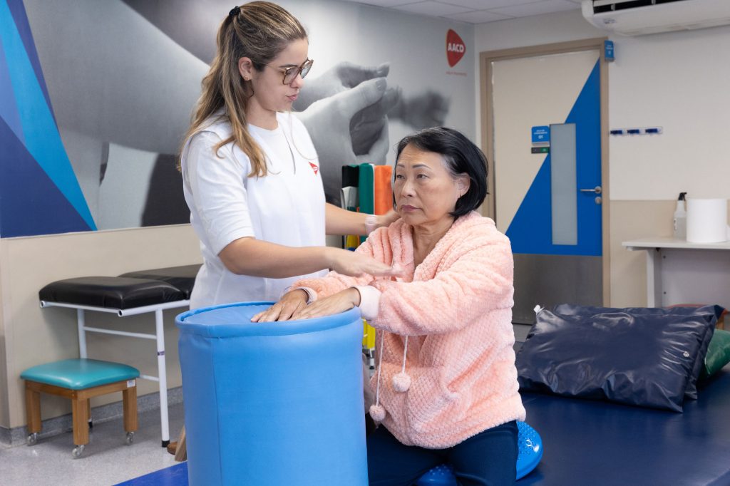 Fisioterapeuta orienta uma paciente idosa durante exercício no Centro de Reabiltação da AACD
