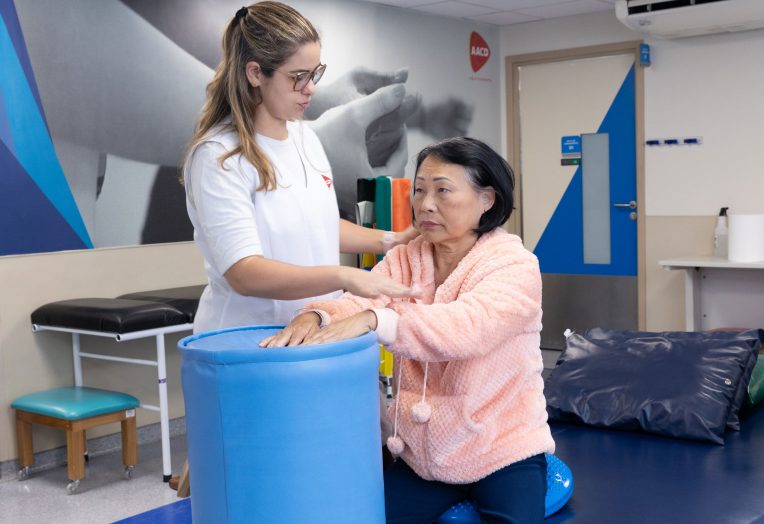 Fisioterapeuta orienta uma paciente idosa durante exercício no Centro de Reabiltação da AACD