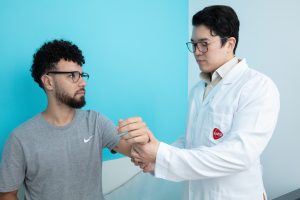 Profissional da AACD realiza avaliação dos movimentos do membro superior de um paciente.