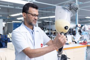 Profissional da AACD ajusta prótese em oficina ortopédica.