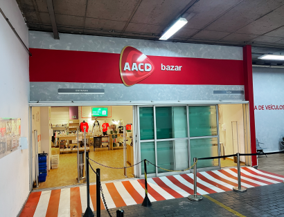 Entrada de bazar da AACD com produtos expostos no interior da loja.