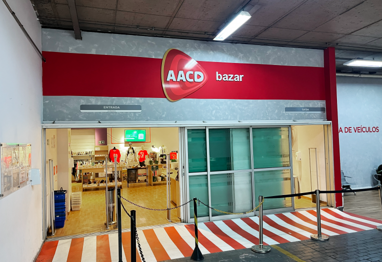 Entrada de bazar da AACD com produtos expostos no interior da loja.