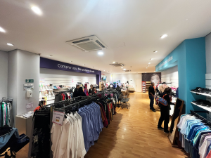 Interior do Bazar da AACD com araras de roupas e produtos diversos.