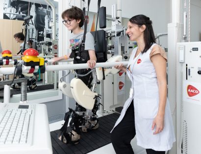 Criança realiza atividade de reabilitação com o equipamento Lokomat e acompanhamento de profissional da AACD.