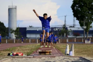 Atleta em pleno salto durante prova de salto em distância em pista de atletismo