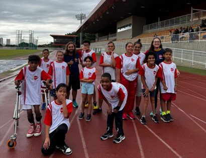 Grupo de atletas da AACD Esportes reunido e uniformizado na pista de atletismo do Centro Paralímpico Brasileiro