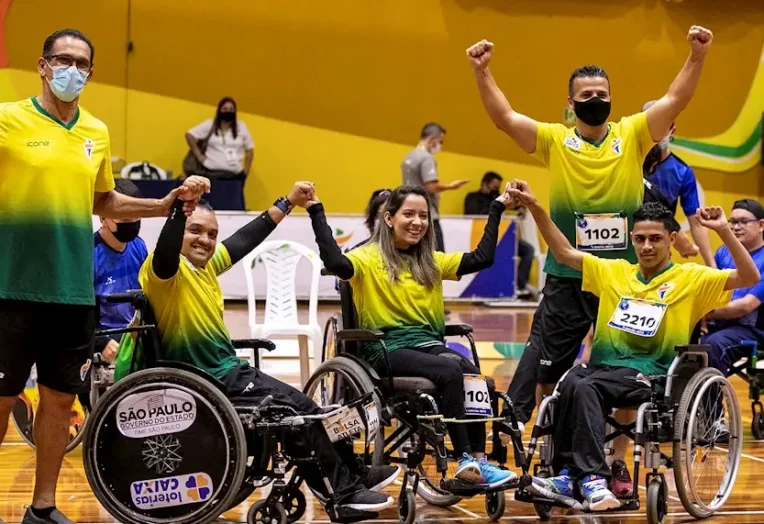 Atletas da bocha paralímpica Maciel Santos, Andreza Oliveira e Iuri Silva comemoram conquista esportiva em quadra.